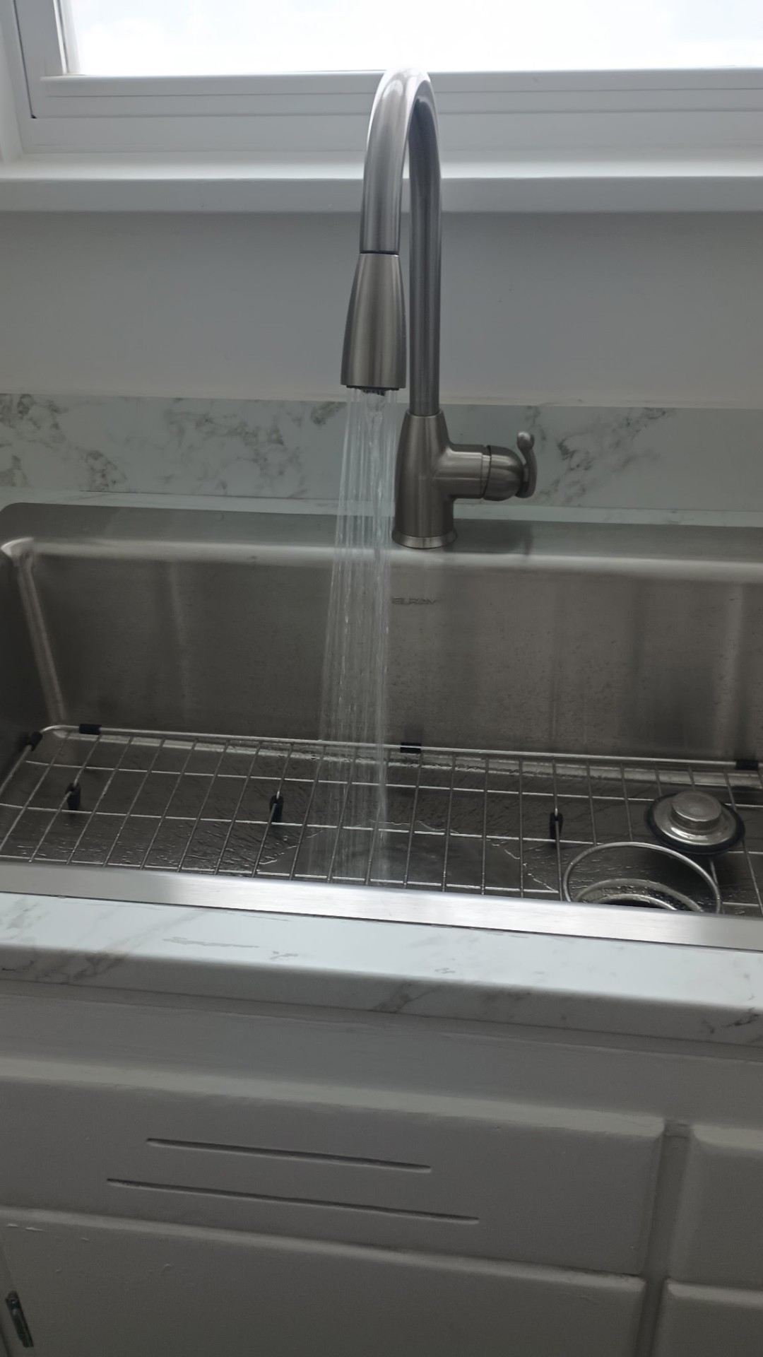 New stainless kitchen sink with marble backsplash